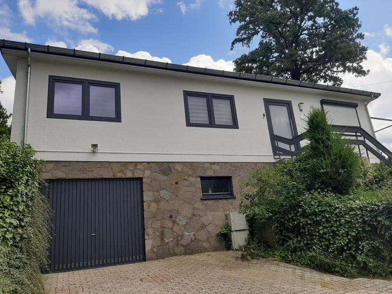 In einem ruhigen Wohnviertel befindet sich dieser schmucke Bungalow mit Blick ins Grüne.
Vom Eingangsflur gelangt man in den Wohnbereich  mit Wohnzimmer und direktem Zugang zur Außen Terrasse und Garten. Direkt angrenzend zum Wohnzimmer befindet sich eine kleine komplett eingerichtete Einbauküche, die über eine Treppe zum Untergeschoss führt.
Über den Eingangsflur gelangt man ebenfalls in den Schlaf und Sanitärbereich. In diesem Bereich befinden sich ein Schlafzimmer von ca. 12 m² sowie ein Büro von ca. 9 m² und ein kleiner Abstell- oder Dressing Raum.
Ergänzt wird das Ganze von einem kleinen, funktionellen Bad mit Handwaschbecken, WC und italienischen Dusche.
Im Untergeschoss befindet sich die Garage sowie ein Keller- und Waschraum.
Das Haus verfügt über eine Gaszentralheizung, eine moderne neue Lüftungsanlage, neue Doppelverglasungsfenster in Anthrazit sowie eine Photovoltaikanlage die die Energiekosten stark reduzieren. Separate Strom-, Gas- und Wasserzähler sowie Rolläden runden das Angebot ab.

