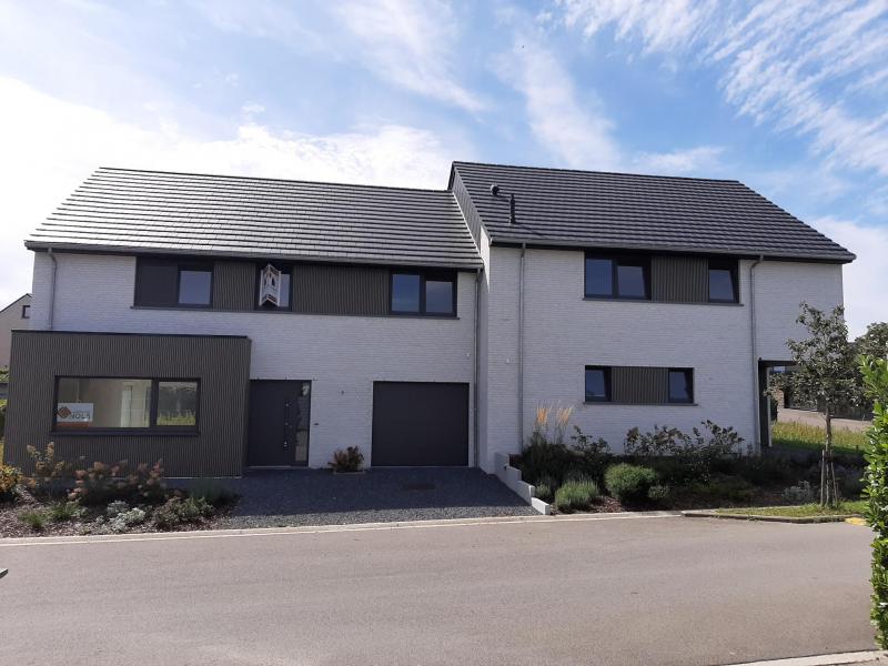 De construction nouvelle, cette maison unifamiliale jumelée à la maison Val du Ru 4 vous offre pratiquement les mêmes avantages que sa soeur avoisinante. De l’espace, de luminosité, sa modernité et une grande efficience énergétique pour passer des bons moments en famille avec ses proches et amis.
Du hall d’entrée avec WC pour invités, on accède au living-salon, inondée de lumière et il dispose d’un accès direct d’une part à la cuisine et d’autre part à la terrasse et jardin (orientation sud-ouest).
Le rez est complété par un grand garage avec une porte sectionelle à ouverture électrique et une partie buanderie. Au garage se trouvent également les compteurs d’électricité, de gaz, de l’eau, la pompe pour récupération de l’eau de pluie (citerne de 10.000 litres) et le chauffage central à gaz de ville. Par ailleurs la maison de type basse énergie (PEB A) dispose d’un chauffage de sol central avec règlage individuel pour chaque pièce, ce qui permet à la fois de combiner du comfort supplémentaire avec de l’éfficience énergétique. A noter également la présence d’une VMC à double flux qui augmente également la qualité de vie.
Un bel escalier en bois vous mène au premier étage avec un hall de nuit, quatre chambres à coucher avec en plus une belle terrasse sur l'annexe du living accessible de la chambre à coucher. Tout comme son voisin un point fort supplémentaire est la salle de bain moderne avec douche italienne, WC et double lavabo avec un meuble ultra moderne.
Bien entendu, cette maison dispose également d’une splendide vue lointaine.
Un grand grenier préaménagé peut servir d'endroit idéal de stockage.
Très belle situation dans un quartier calme, près de toutes les commodités et l’accès autoroutier.
N’hésitez pas et venez visiter cette maison offrant un haut standing de qualité de vie, de modernité et un niveau de finition élevée.
