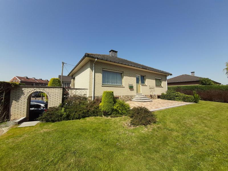 Cette maison est située au bout d'un cul de sac, qui garantit une tranquilité totale. Maison en parfait état et très soignée. Ce bungalow a été construit en 1976 et dispose de deux chambres à coucher avec la possibilité d'en faire une chambre supplémentaire soit au niveau des caves, soit au niveau du grenier ou même les deux. Entouré d'un joli jardin la parcelle s'étend sur 656 m².
La surface habitable est de +/- 87 m² et se compose comme suit, hall d'entrée avec un WC, grand living qui abrite une cheminée ouverte non-utilisée mais avec la possiblité de l'activer, cuisine partiellement meublée avec accès à la terrasse et son jardin avec orientation sud-est. De plus il y a deux chambres à coucher, une salle de bain avec douche, double lavabo et baignoire. Grand grenier, qui pourrait abriter une chambre supplémentaire. Toute la maison est sous cave avec un très grand garage, qui offre de la place pour deux voitures, une buanderie, un SAS avec lavabo et urinoir et finalement le chauffage au gaz de la marque 